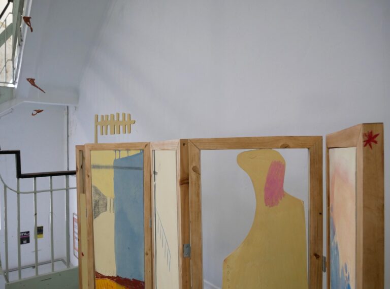 close-up of wooden folding structure with painting inserts in white hallway