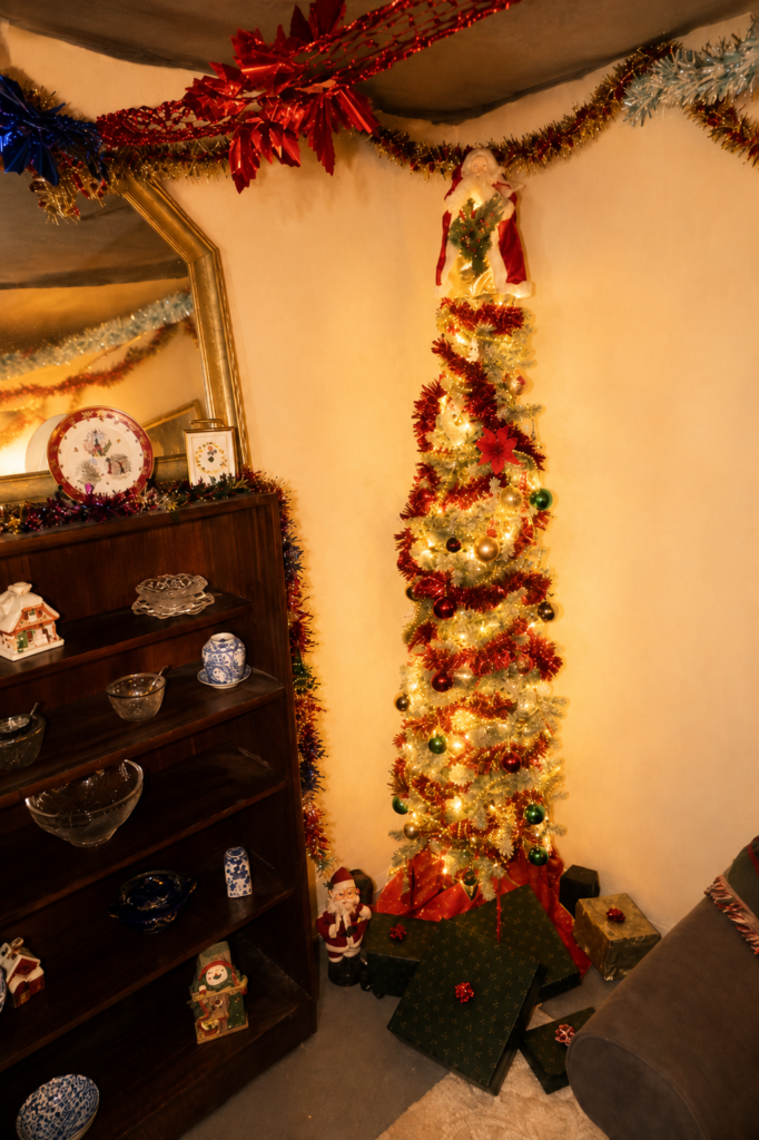 Installation detail showing a decorated Christmas tree, vintage shelving unit and domestic interior setting