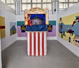 Installation view of House Rules featuring Punch and Judy booth and surrounding artworks
