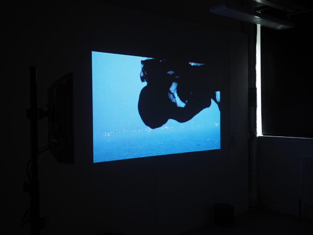 a projection in a dark room of ink spreading out over a gloomy seascape