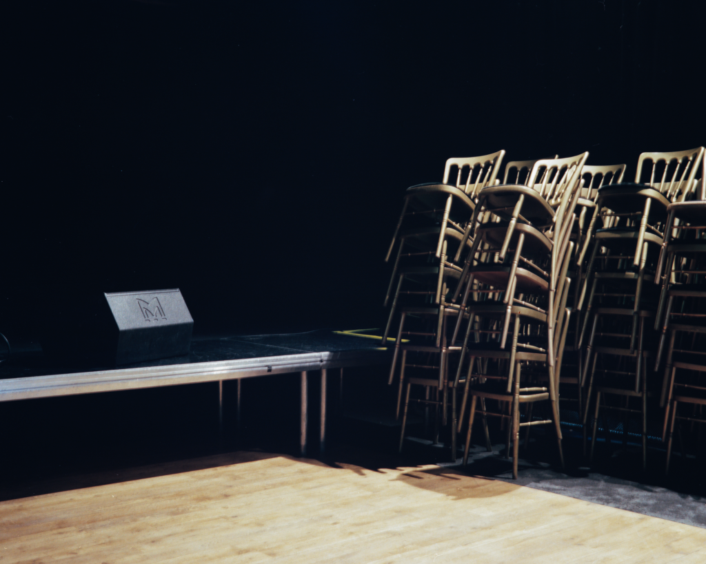 Stacked chairs beside an empty stage.