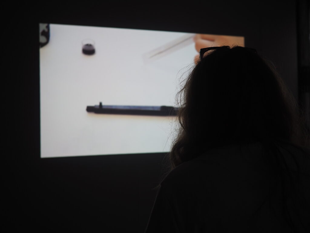 over the shoulder view of a projection showing a tattoo needle on a white background
