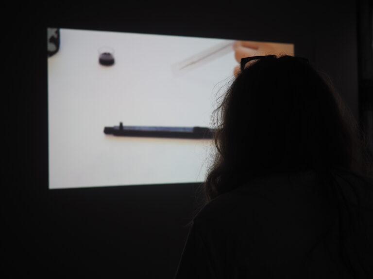 over the shoulder view of a projection showing a tattoo needle on a white background