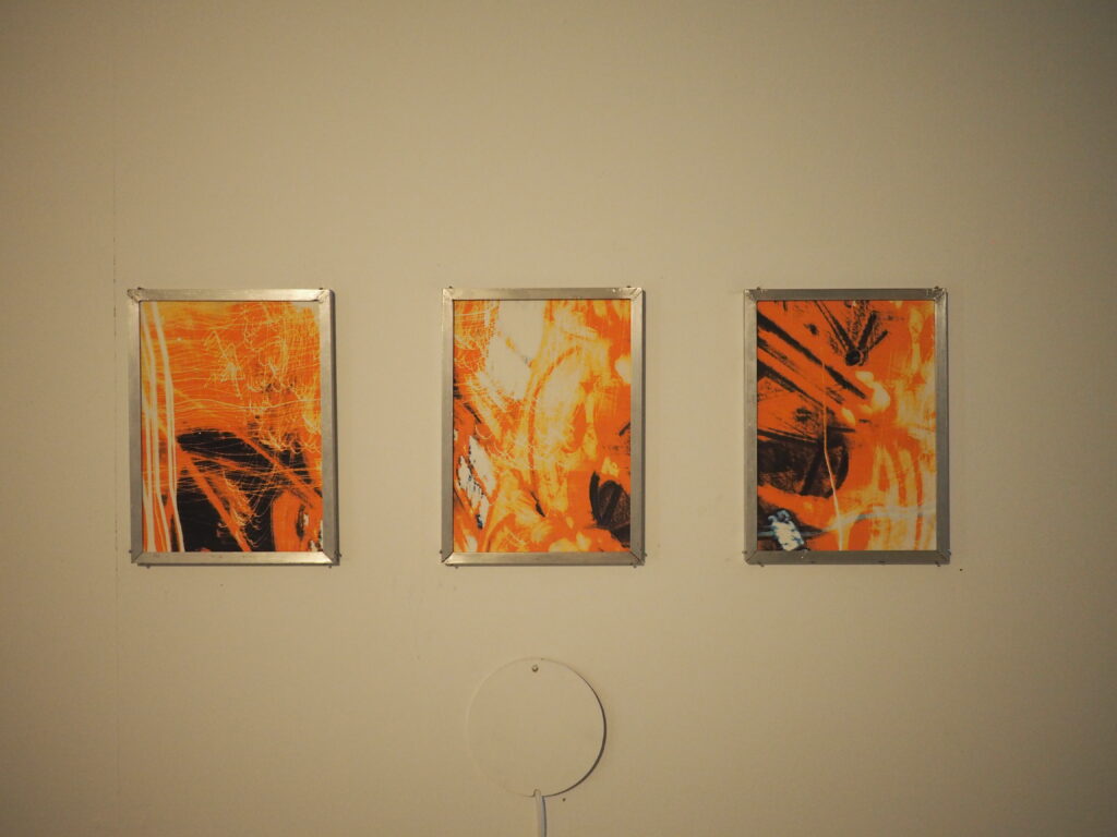 three orange prints framed in metal on a wall