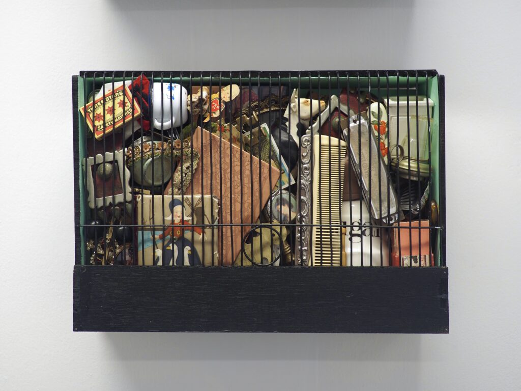 A wooden canary show cage filled with personal trinkets
